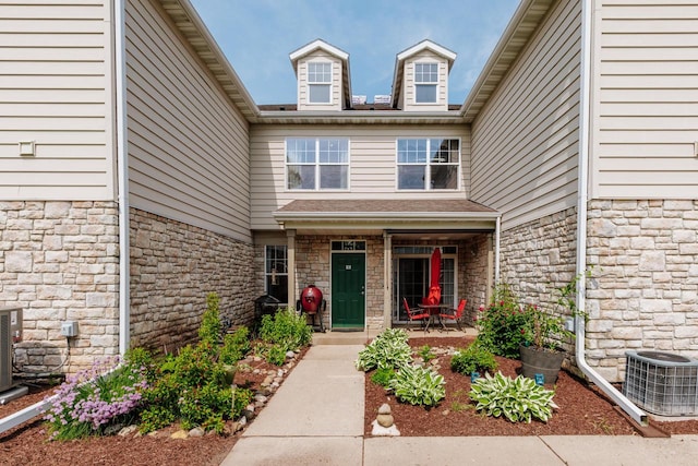 N17W26535 Meadowgrass Cir Unit G, Pewaukee, WI 53072 - entrance to property with central air condition unit, stone siding, and a porch
