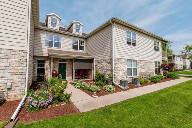 N17W26535 Meadowgrass Cir Unit G, Pewaukee, WI 53072 - view of front of property with stone siding, central air condition unit, and a front lawn