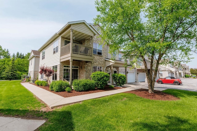 N17W26535 Meadowgrass Cir Unit G, Pewaukee, WI 53072 - townhome / multi-family property with stone siding, a balcony, a front yard, driveway, and a garage