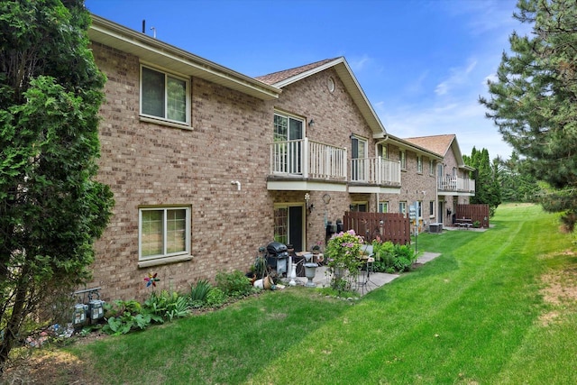 1507 Clarence Ct Unit 5, West Bend, WI 53095 - back of house featuring a patio, a balcony, brick siding, a lawn, and central AC