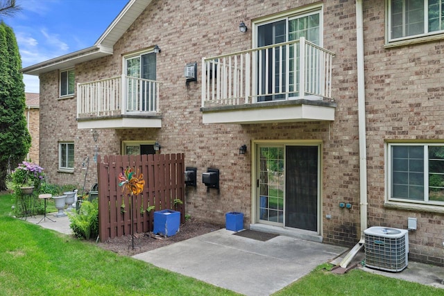 1507 Clarence Ct Unit 5, West Bend, WI 53095 - back of house featuring a balcony, central AC unit, a patio, and brick siding