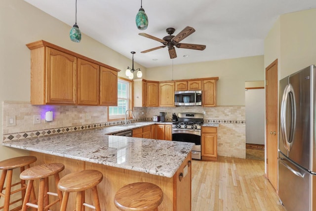 2432 Forest Hill Ct, Waukesha, WI 53188 - kitchen featuring stainless steel appliances, a peninsula, a ceiling fan, light wood-type flooring, and a sink