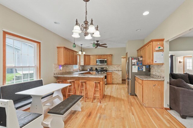 2432 Forest Hill Ct, Waukesha, WI 53188 - kitchen featuring appliances with stainless steel finishes, a sink, a peninsula, a chandelier, and light wood-type flooring