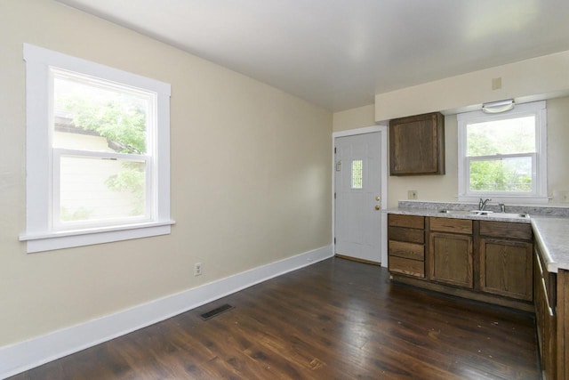 912 Harvey St, Beloit, WI 53511 - kitchen with a sink, baseboards, dark wood-type flooring, and light countertops