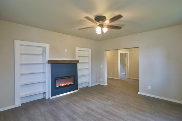 1226 Bellevue Ave, Eau Claire, WI 54703 - unfurnished living room featuring ceiling fan, a glass covered fireplace, baseboards, dark wood-type flooring, and built in features
