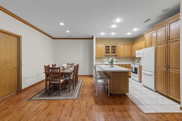 6758 Raymond Rd Unit 109, Madison, WI 53719 - kitchen with white appliances, crown molding, a kitchen island, light countertops, and a kitchen bar
