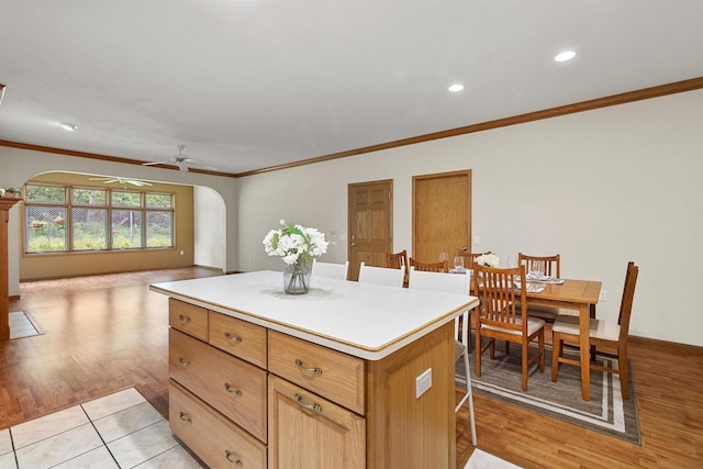 6758 Raymond Rd Unit 109, Madison, WI 53719 - kitchen with arched walkways, ornamental molding, ceiling fan, a kitchen island, and light wood-type flooring