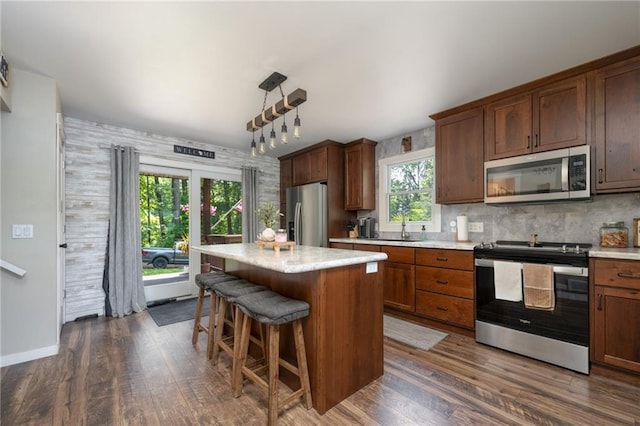 kitchen with stainless steel appliances, dark wood-style floors, light countertops, a center island, and a breakfast bar