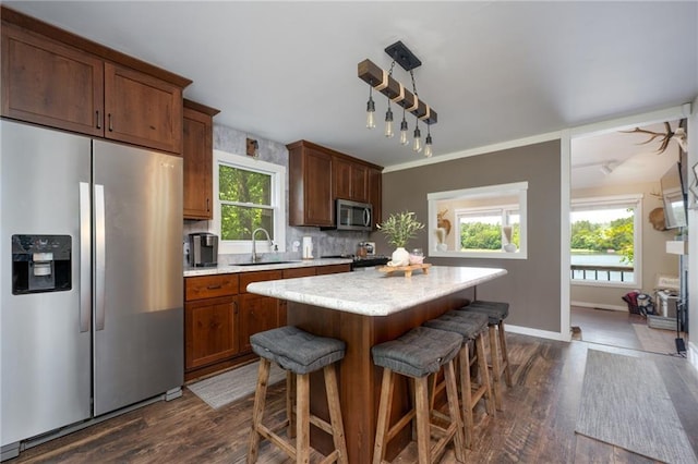 kitchen featuring appliances with stainless steel finishes, a sink, dark wood-style floors, and light countertops