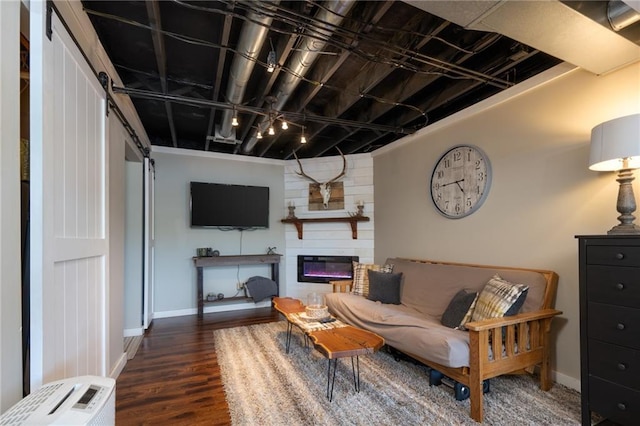 living area featuring a barn door, baseboards, wood finished floors, and a large fireplace