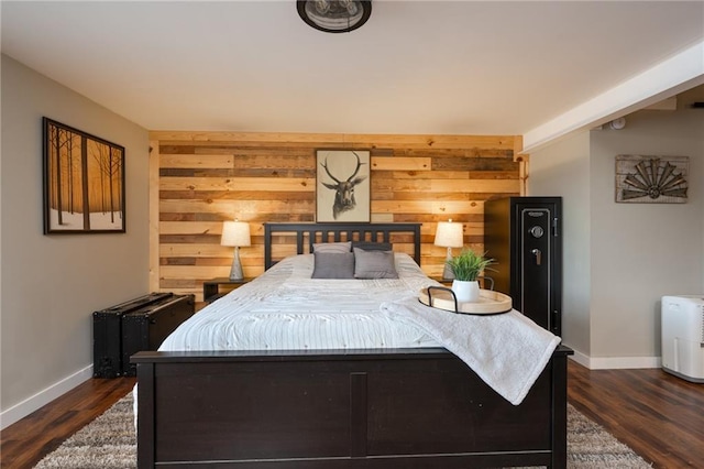 bedroom featuring baseboards, wood walls, and dark wood-type flooring