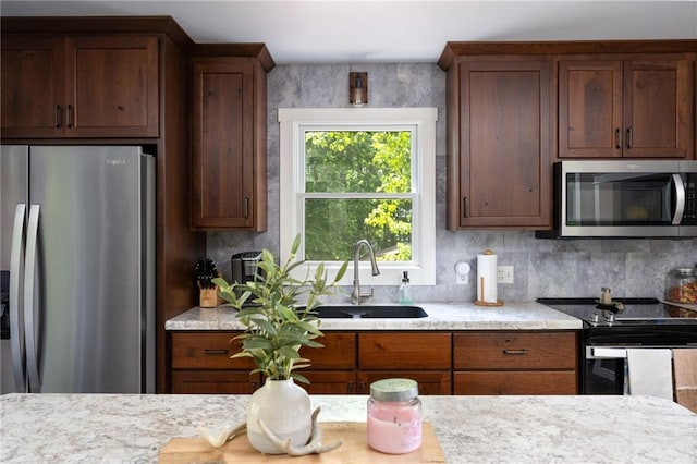 kitchen with stainless steel appliances, a sink, and light stone counters