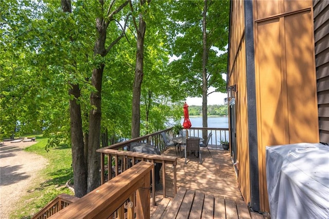 wooden deck featuring outdoor dining area, a water view, and grilling area