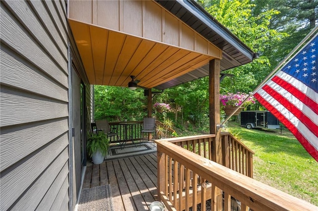 wooden terrace with ceiling fan and a lawn