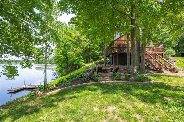 view of grassy yard featuring stairway, a deck with water view, a floating dock, and a patio area