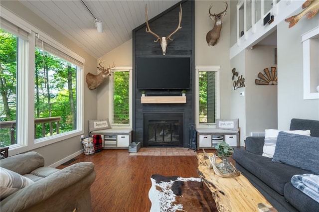 living area with lofted ceiling, a fireplace, wood finished floors, baseboards, and wooden ceiling