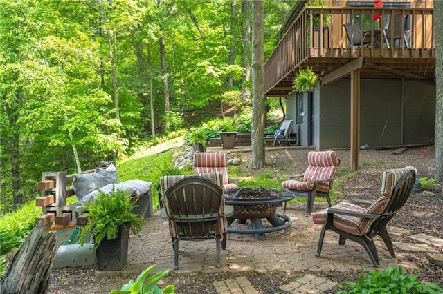 view of patio with a fire pit, a deck, and a wooded view