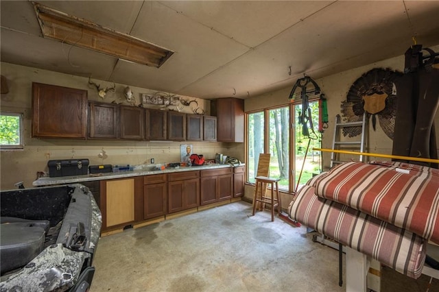 kitchen with unfinished concrete flooring, light countertops, and brown cabinetry