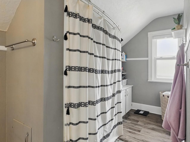 409 Huron St, Manitowoc, WI 54220 - full bathroom featuring lofted ceiling, baseboards, a shower with shower curtain, wood finished floors, and a textured ceiling