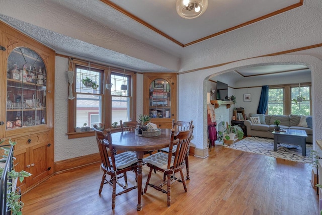 2116 N 60th St Unit 2118, Milwaukee, WI 53208 - dining area featuring a textured wall, arched walkways, baseboards, light wood-type flooring, and crown molding