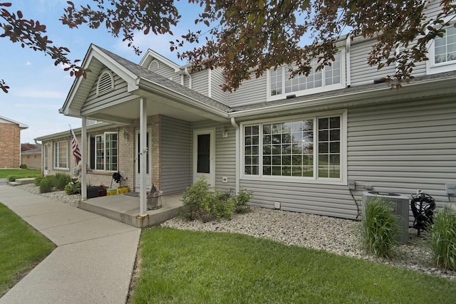 10380 W Whitnall Edge Cir Unit F, Franklin, WI 53132 - view of property exterior with a yard, roof with shingles, central AC, and brick siding