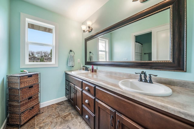 905 W Hubble Ln, Appleton, WI 54913 - bathroom featuring baseboards, double vanity, and stone finish floors