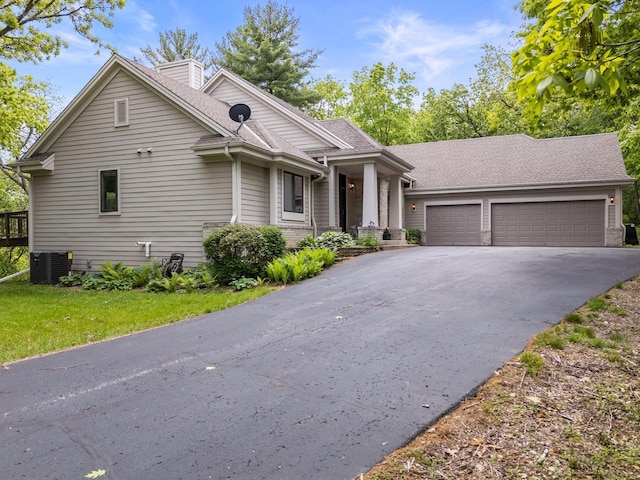 W3847 Timber Lake Rd, East Troy, WI 53120 - view of front of house with an attached garage, driveway, a shingled roof, cooling unit, and a chimney
