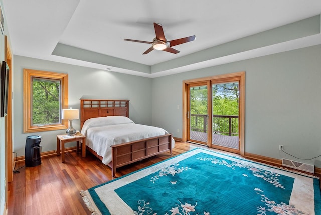 W3847 Timber Lake Rd, East Troy, WI 53120 - bedroom featuring access to exterior, multiple windows, a tray ceiling, and hardwood / wood-style floors