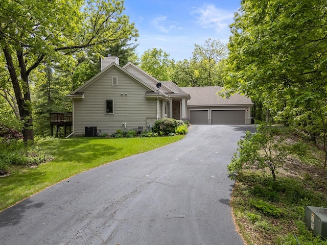 W3847 Timber Lake Rd, East Troy, WI 53120 - view of front of home featuring a garage, asphalt driveway, a chimney, a front yard, and cooling unit