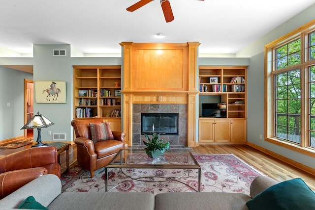W3847 Timber Lake Rd, East Troy, WI 53120 - living room with a tiled fireplace, light wood finished floors, a ceiling fan, baseboards, and built in features