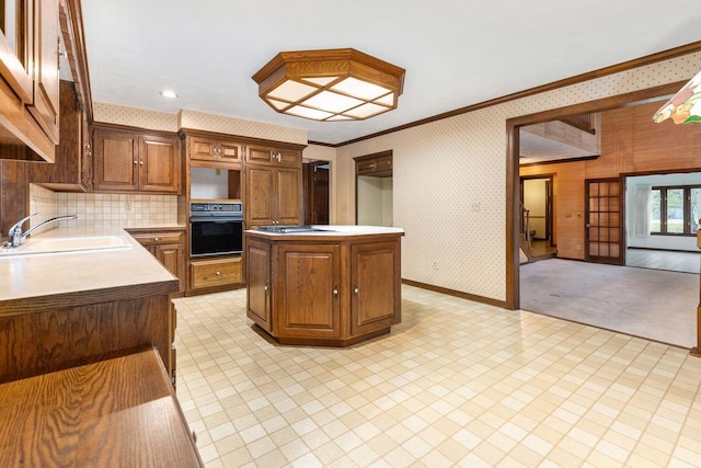 28 W Lake Rd, Menasha, WI 54952 - kitchen with black oven, a sink, light countertops, a center island, and crown molding