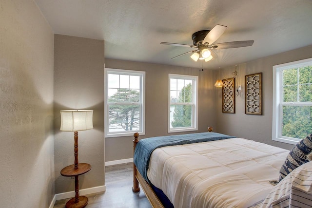 2320 Wilson St, Two Rivers, WI 54241 - bedroom featuring baseboards, multiple windows, wood finished floors, and a ceiling fan