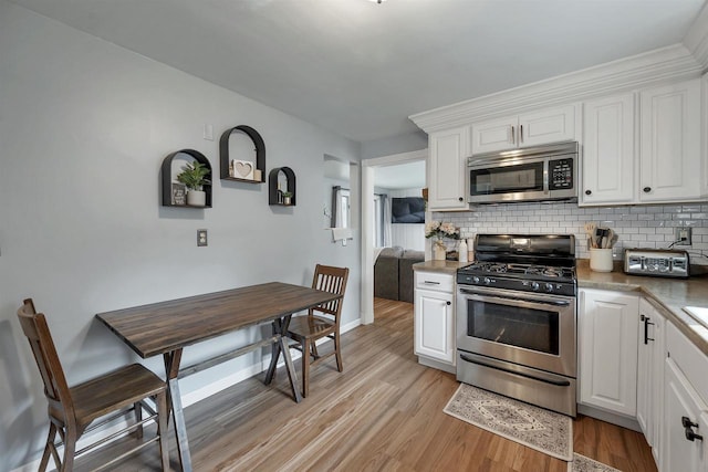 3813 S Clay St, Green Bay, WI 54301 - kitchen with stainless steel appliances, decorative backsplash, light wood-type flooring, and white cabinetry
