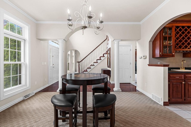 139 Sullivan Ln, De Pere, WI 54115 - dining room featuring light carpet, ornamental molding, decorative columns, a chandelier, and wet bar
