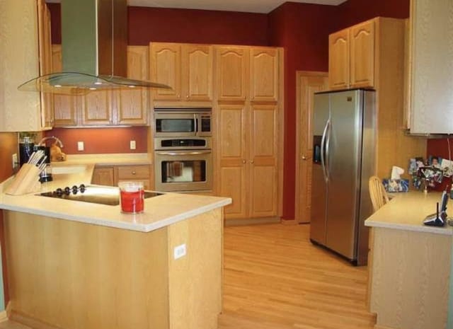 10 Vienna Cir, Madison, WI 53718 - kitchen with appliances with stainless steel finishes, wall chimney range hood, light wood-style floors, light countertops, and a peninsula