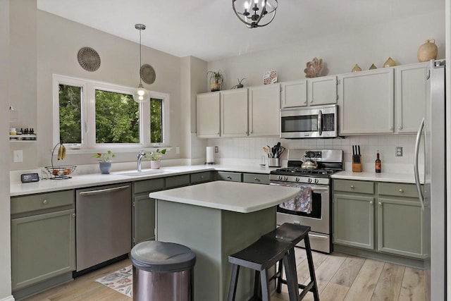 20506 83rd Pl, Bristol, WI 53104 - kitchen featuring appliances with stainless steel finishes, a sink, light countertops, light wood-style floors, and hanging light fixtures