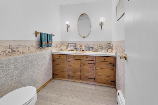 1616 7th St, Menomonie, MI 49858 - bathroom featuring a baseboard heating unit, vanity, toilet, a wainscoted wall, and wood finished floors