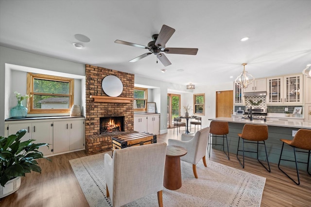 4062 S 106th St, Greenfield, WI 53228 - living area featuring a brick fireplace, plenty of natural light, recessed lighting, a chandelier, and light wood-style flooring