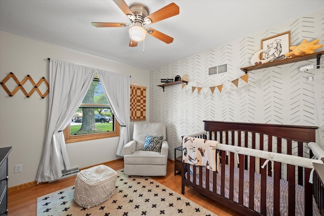 4062 S 106th St, Greenfield, WI 53228 - bedroom with a crib, ceiling fan, wood finished floors, and baseboards