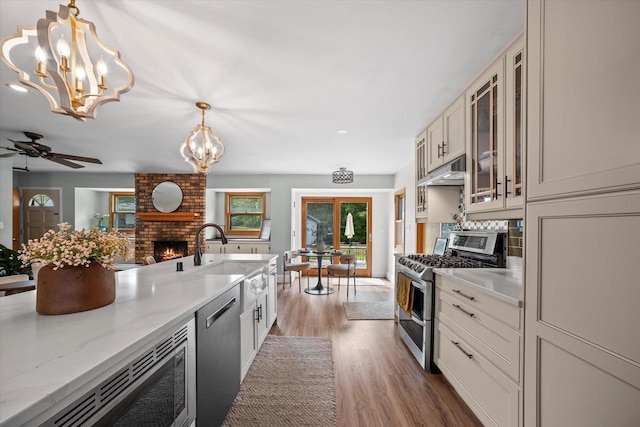4062 S 106th St, Greenfield, WI 53228 - kitchen featuring appliances with stainless steel finishes, a sink, a chandelier, a fireplace, and wood finished floors