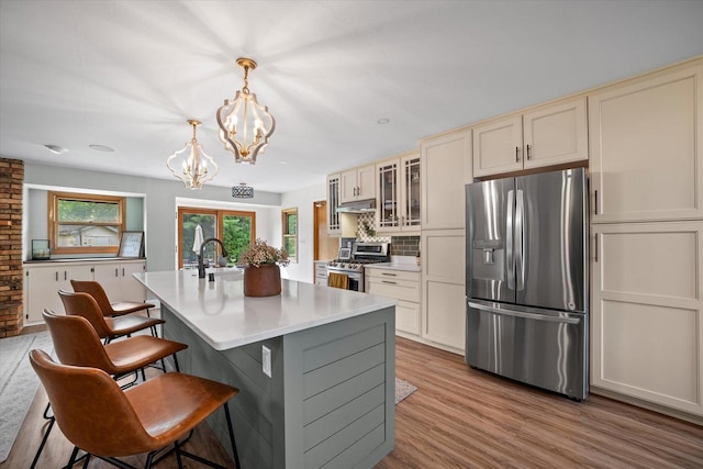 4062 S 106th St, Greenfield, WI 53228 - kitchen with appliances with stainless steel finishes, a chandelier, light countertops, a kitchen island with sink, and under cabinet range hood