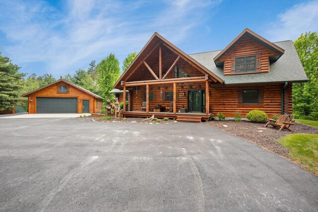 W6034 N Lake Dr, New Lisbon, WI 53950 - cabin featuring log exterior, a detached garage, an outdoor structure, covered porch, and roof with shingles