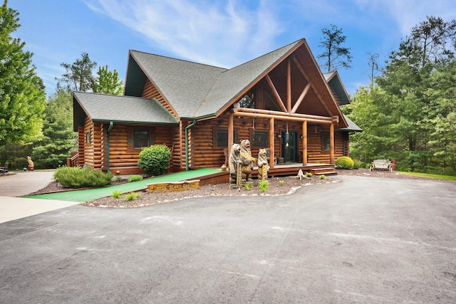 W6034 N Lake Dr, New Lisbon, WI 53950 - log-style house with log exterior, covered porch, asphalt driveway, and roof with shingles
