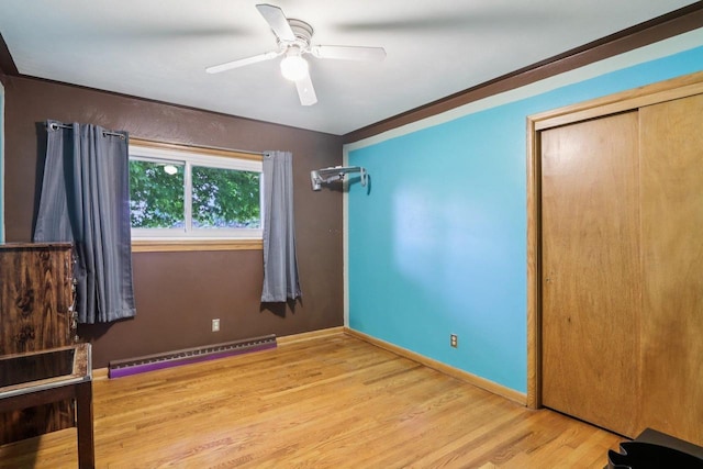 109 County Park Rd, Waupun, WI 53963 - unfurnished bedroom featuring baseboard heating, wood finished floors, a closet, a ceiling fan, and baseboards