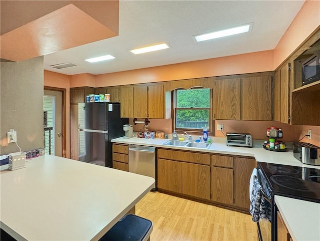 711 Cleveland Ave, Ladysmith, WI 54848 - kitchen featuring black appliances, light countertops, a sink, light wood-type flooring, and a peninsula