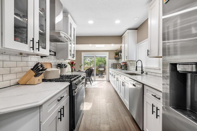1514 S 96th St, West Allis, WI 53214 - kitchen with stainless steel appliances, a sink, wall chimney range hood, wood finished floors, and white cabinets