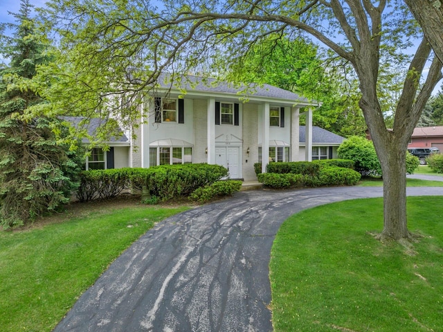 15075 Kings Ridge Ct, Brookfield, WI 53005 - neoclassical / greek revival house featuring curved driveway, a front yard, stucco siding, and roof with shingles