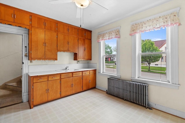 3700 E Hammond Ave, Cudahy, WI 53110 - kitchen with radiator, light countertops, brown cabinetry, a sink, and a ceiling fan