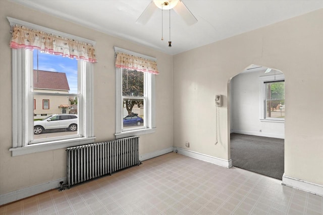 3700 E Hammond Ave, Cudahy, WI 53110 - empty room featuring radiator heating unit, a ceiling fan, healthy amount of natural light, and arched walkways