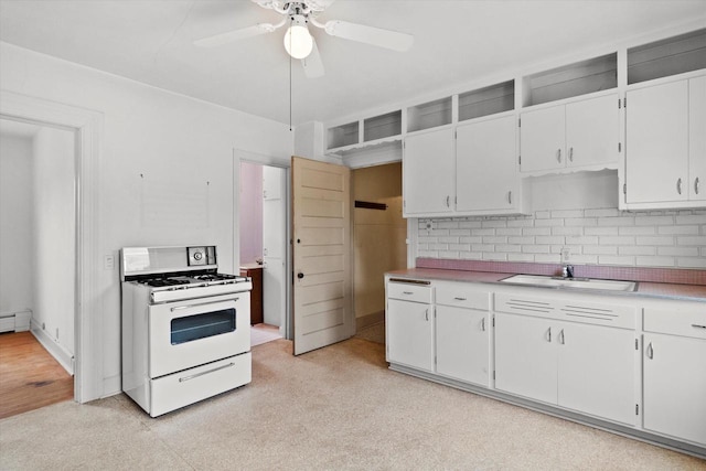3700 E Hammond Ave, Cudahy, WI 53110 - kitchen with white gas stove, a sink, decorative backsplash, a ceiling fan, and light countertops